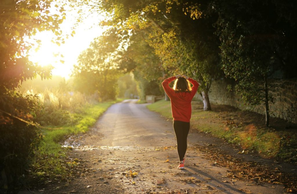 Woman walking along path in afternoon sunlight