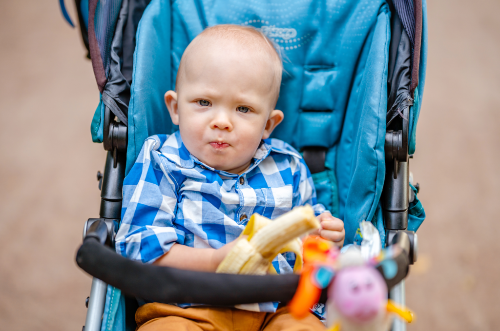 Kid snacking on banana whilst sitting in stroller