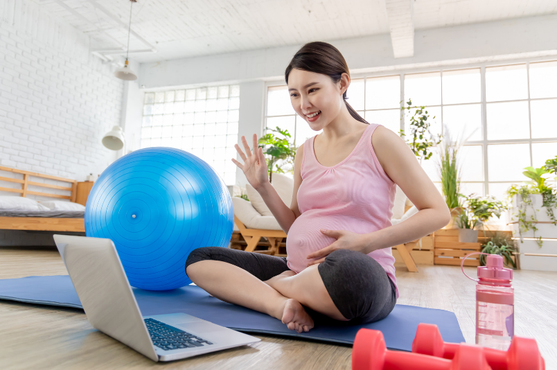 pregnant mom using laptop for virtual workout exercise