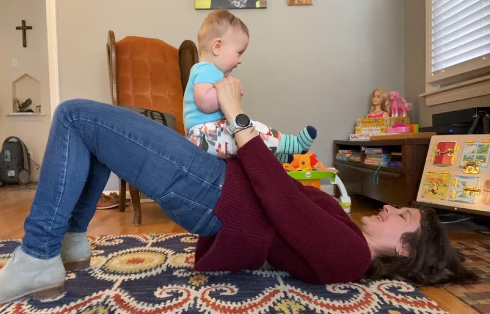 Happy mom doing glute bridges with baby